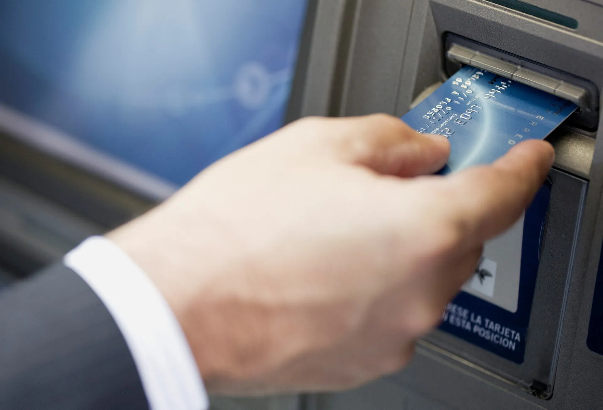 Hand inserting card into an ATM machine.